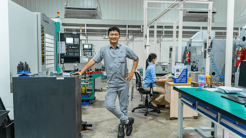 CAM Resources technician chuckles while posing by the shopfloor
